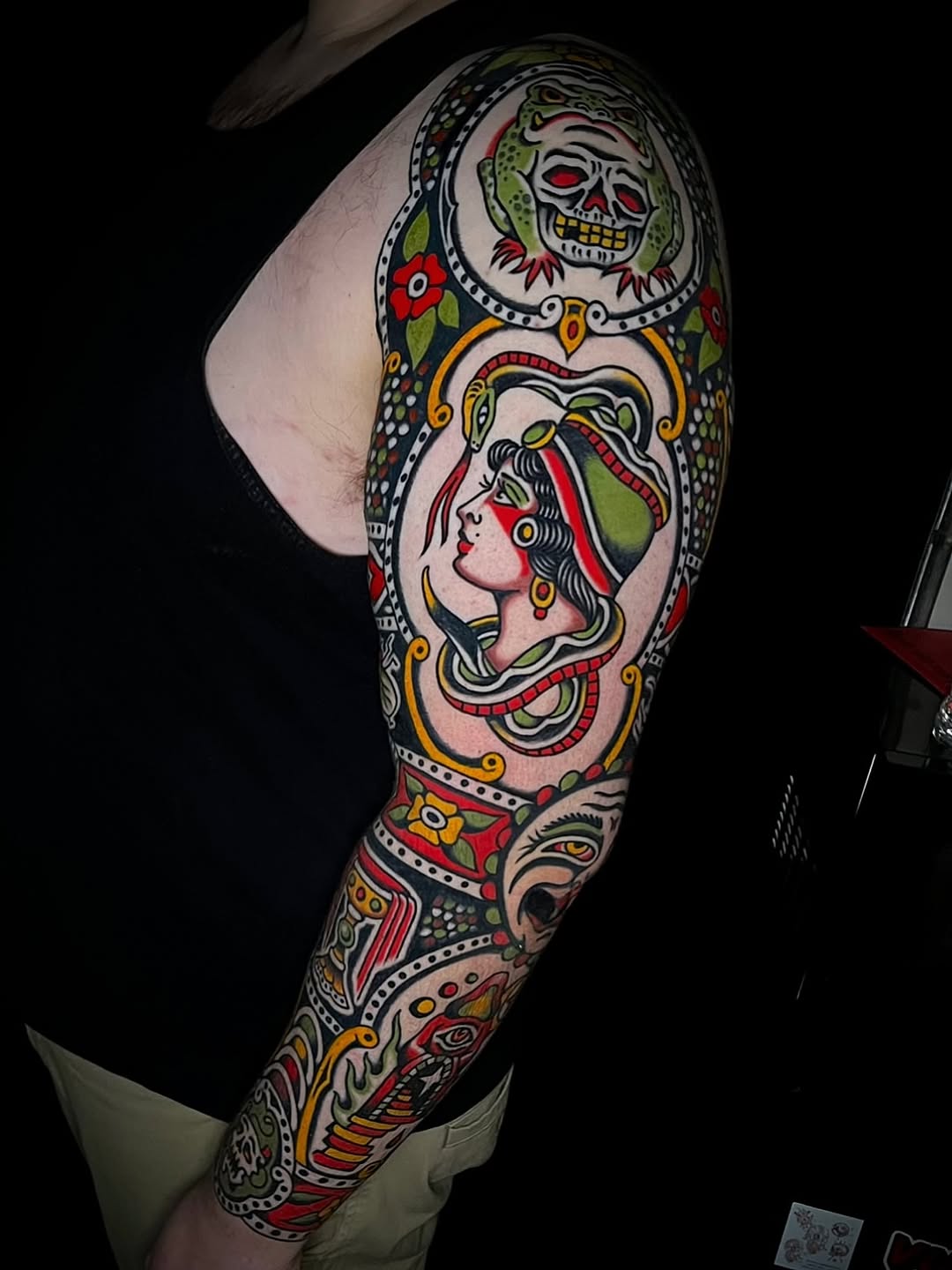 Full arm sleeve featuring skull with lizard, female profile portrait, and decorative floral elements in traditional style.