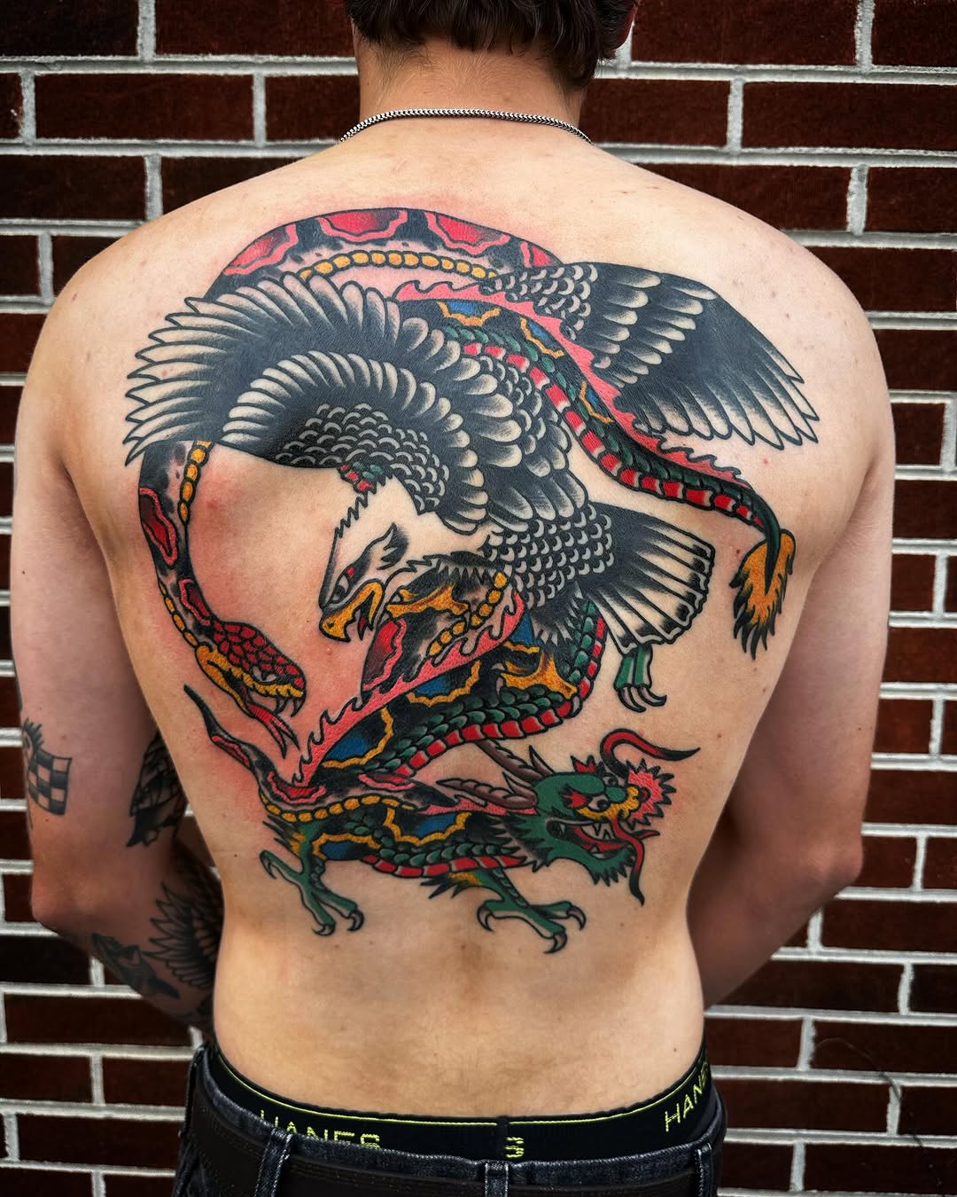 Eagle and dragon back piece with bold black outlines, red and yellow accents, and traditional Americana imagery on upper back.