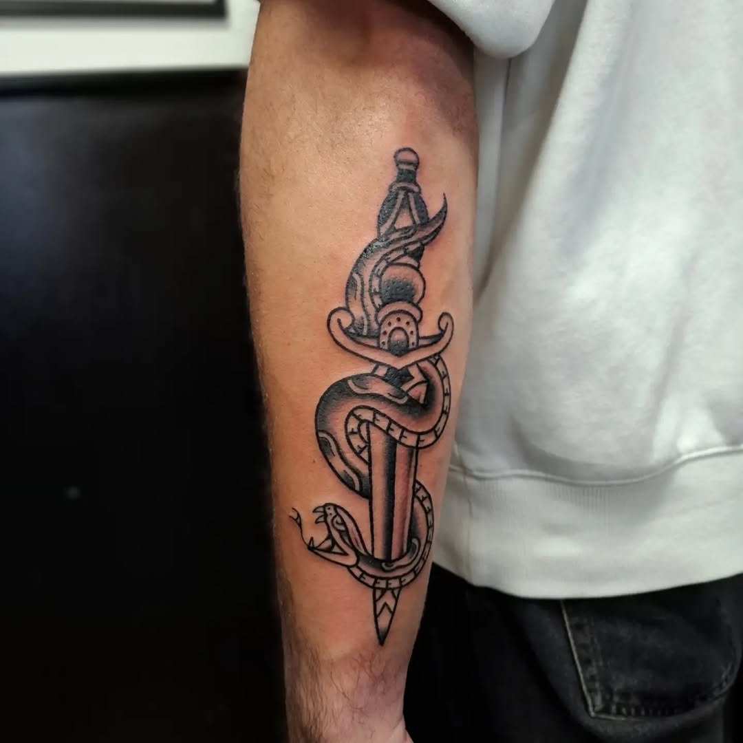 Classic anchor with two snakes wrapped around it and a dagger through the center, on the forearm.