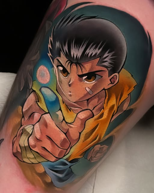 Hisoka from Hunter x Hunter tattooed on an arm, wearing yellow jacket with pink cards, against blue-green background.
