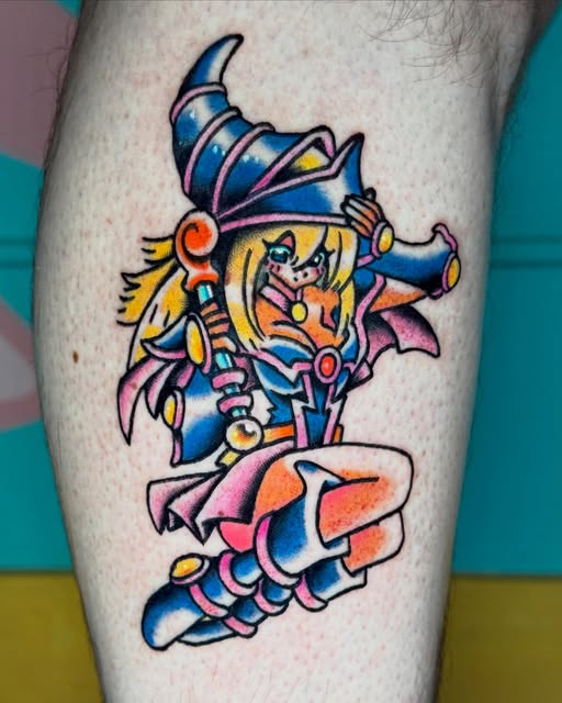 Colorful tattoo of a jester or clown character with blue hat, yellow hair, and red nose on a calf, surrounded by pink and orange ribbons.