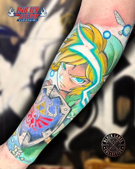 Link from The Legend of Zelda character tattoo on forearm featuring blonde hair, green tunic, blue eyes, shield with Triforce symbol, and lightning bolt effects in yellow, green, blue, and red.