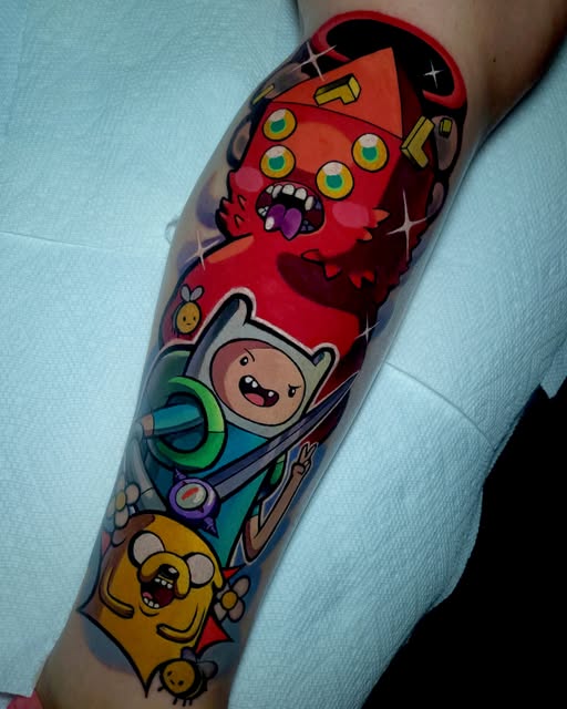 Adventure Time characters including Finn, Jake the Dog, and the Ice King tattooed on a person's forearm in bright red, blue, yellow, and orange colors.