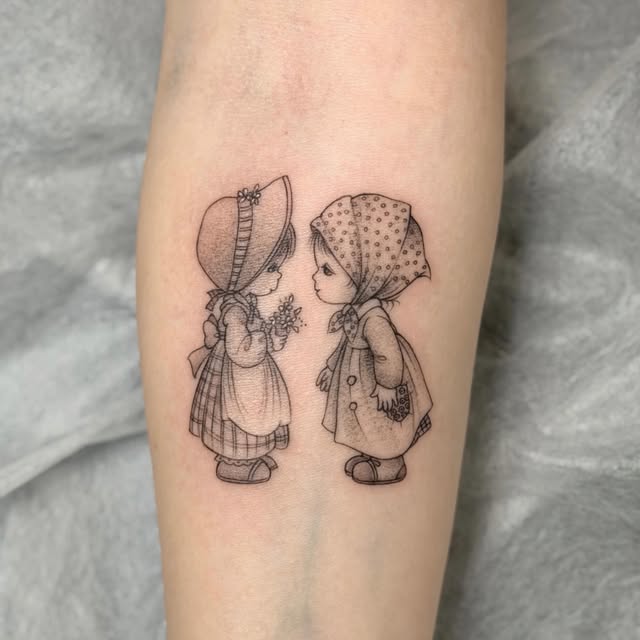 Sunbonnet Sue characters facing each other on forearm, one holding flowers, rendered in fine black line work with dotted details.