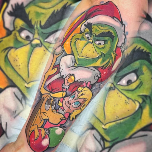 The Grinch in red Santa suit holding a candy cane and small character, surrounded by multiple Grinch face designs in greens and yellows on forearm.