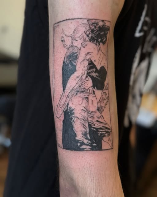 Monochrome tattoo on forearm depicting an anime character in dynamic pose with flowing hair and clothing details rendered in black ink.