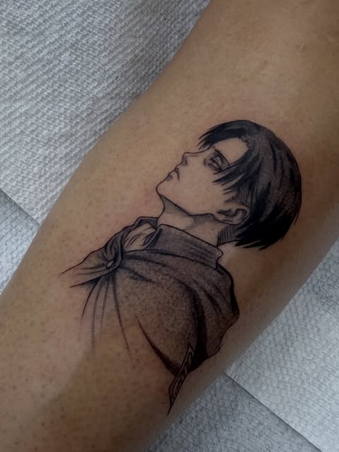 Black and grey tattoo on an arm depicting a person with short dark hair in profile, wearing a collared shirt, looking upward with a contemplative expression.
