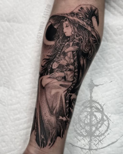 A detailed black and grey tattoo on the forearm depicts a woman with long flowing hair wearing an ornate hat, holding a staff, with a crescent moon and mystical symbols below.
