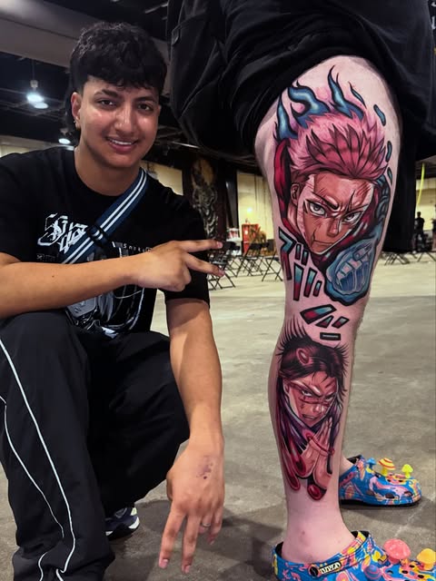 Man displaying a full-leg tattoo featuring Yuji Itadori from Jujutsu Kaisen in pink and blue tones, with additional character elements below on his calf.