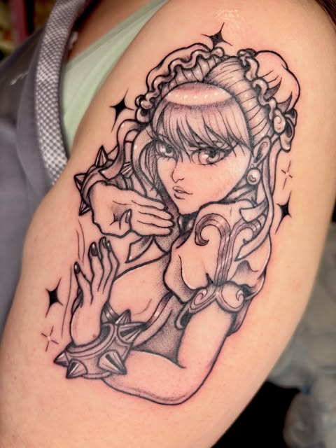 Anime girl with long bangs and ornate decorative frame featuring spikes and flourishes, adorned with stars, tattooed on upper arm in black ink.