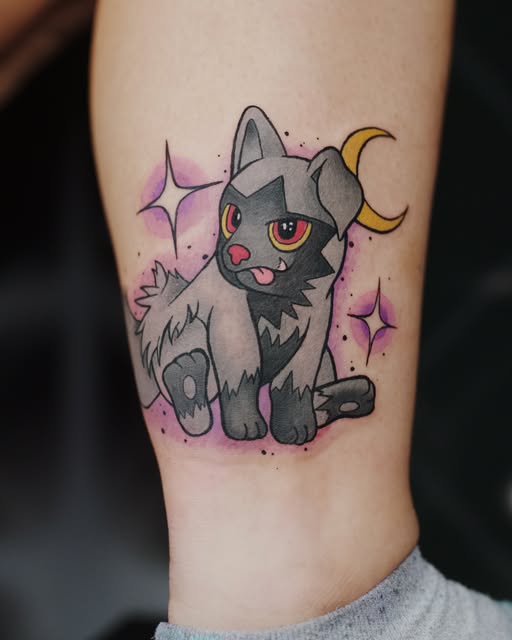 Litten, a dark gray cat Pokémon with orange eyes and a crescent moon, tattooed on an arm with purple sparkles and celestial elements.