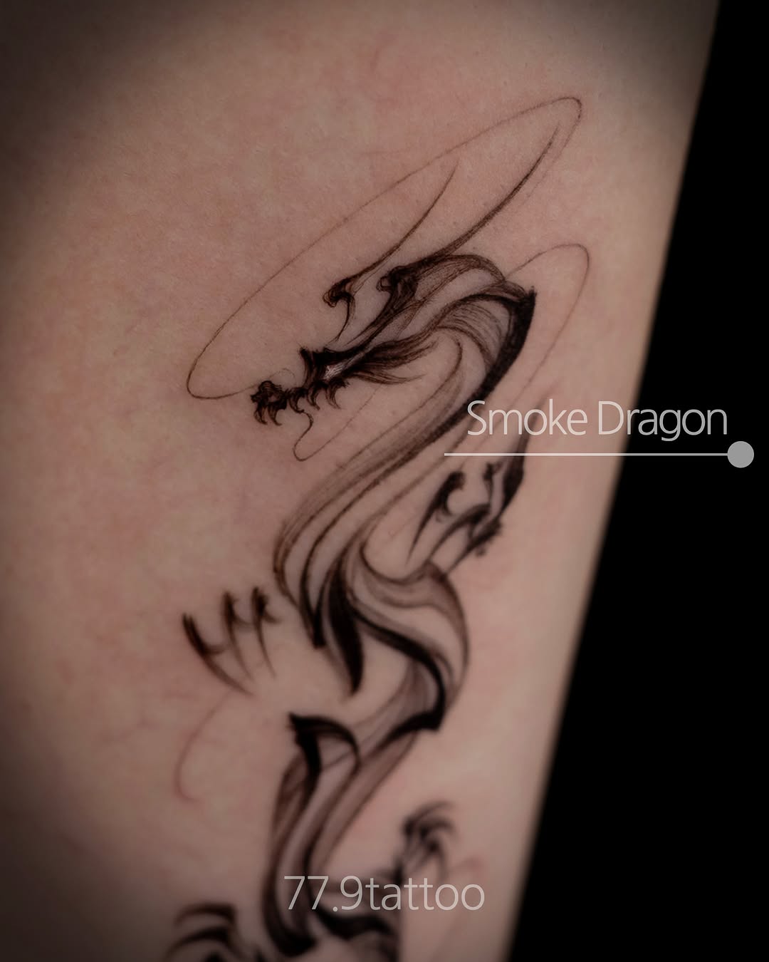 Smoke dragon tattoo with flowing body, intricate linework, and atmospheric wisps on arm.