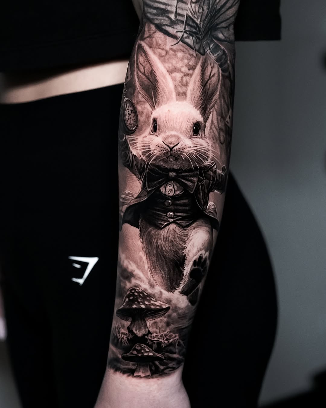 Black and grey realistic portrait tattoo of a fancy dressed rabbit wearing a bow tie and formal jacket on forearm.