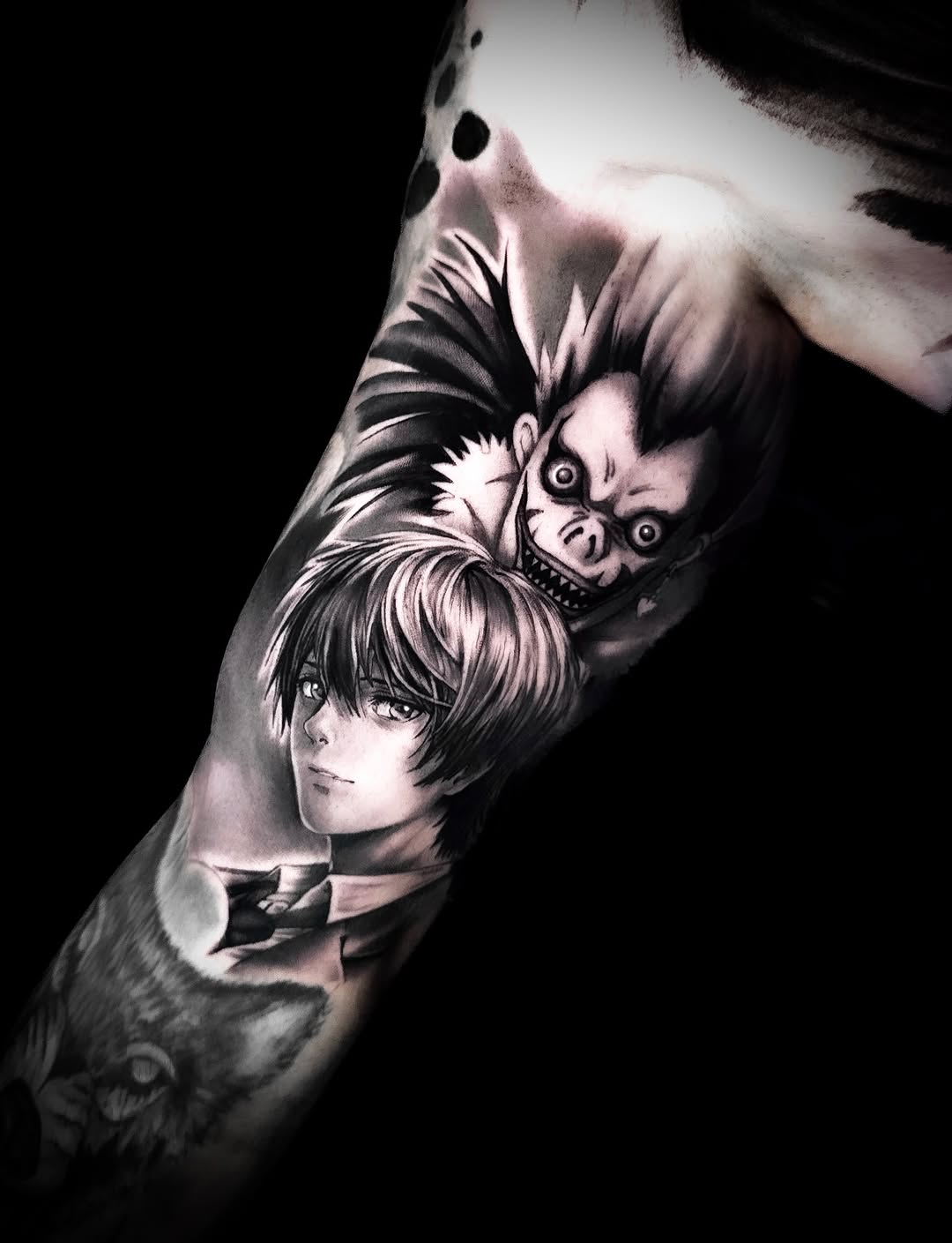 Monochromatic anime-style portrait tattoo on forearm featuring two characters with detailed facial expressions and shading.