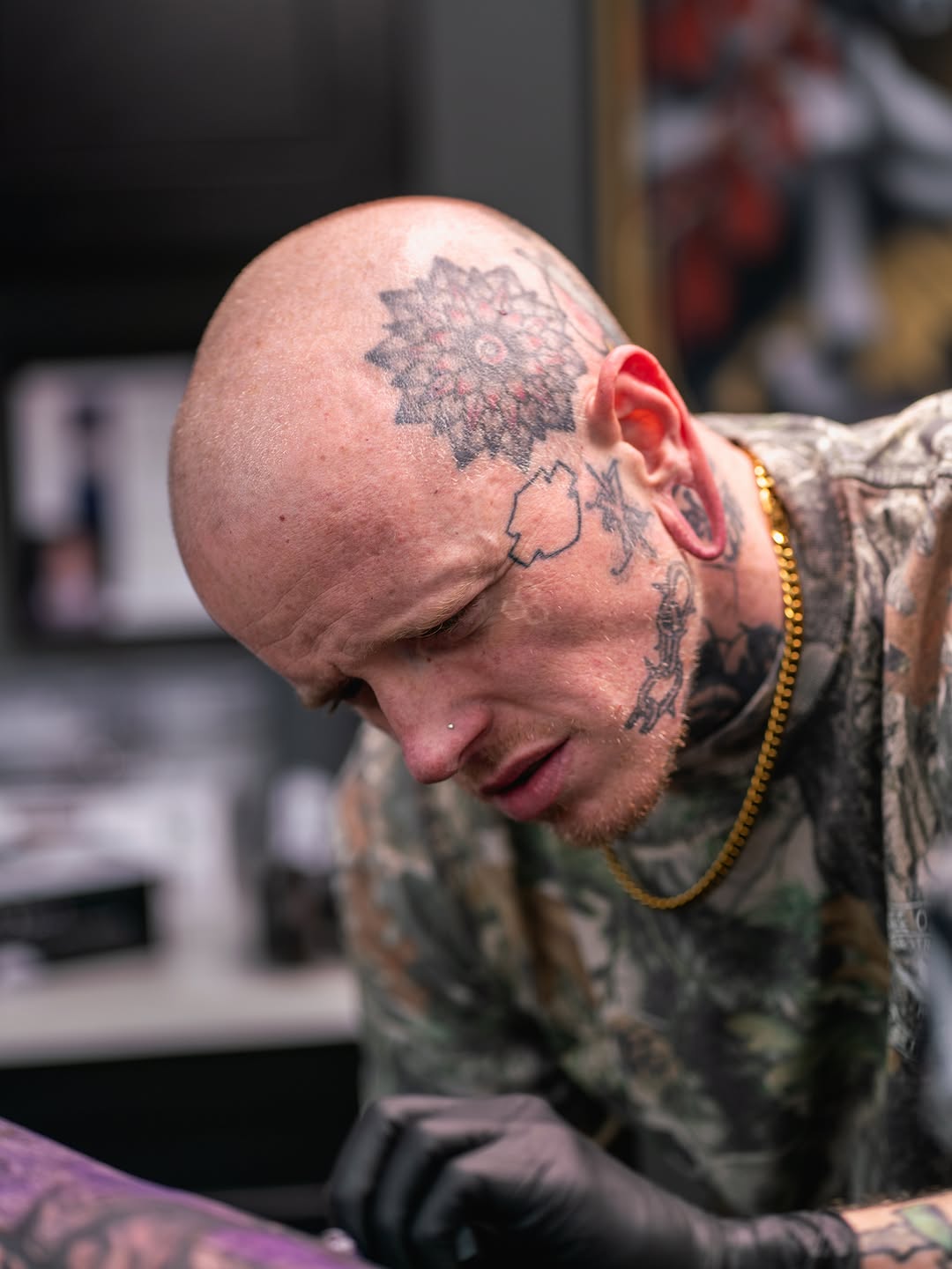 Black and grey portrait tattoo of a wolf's head on the scalp of a bald man, showing realistic shading and detail.