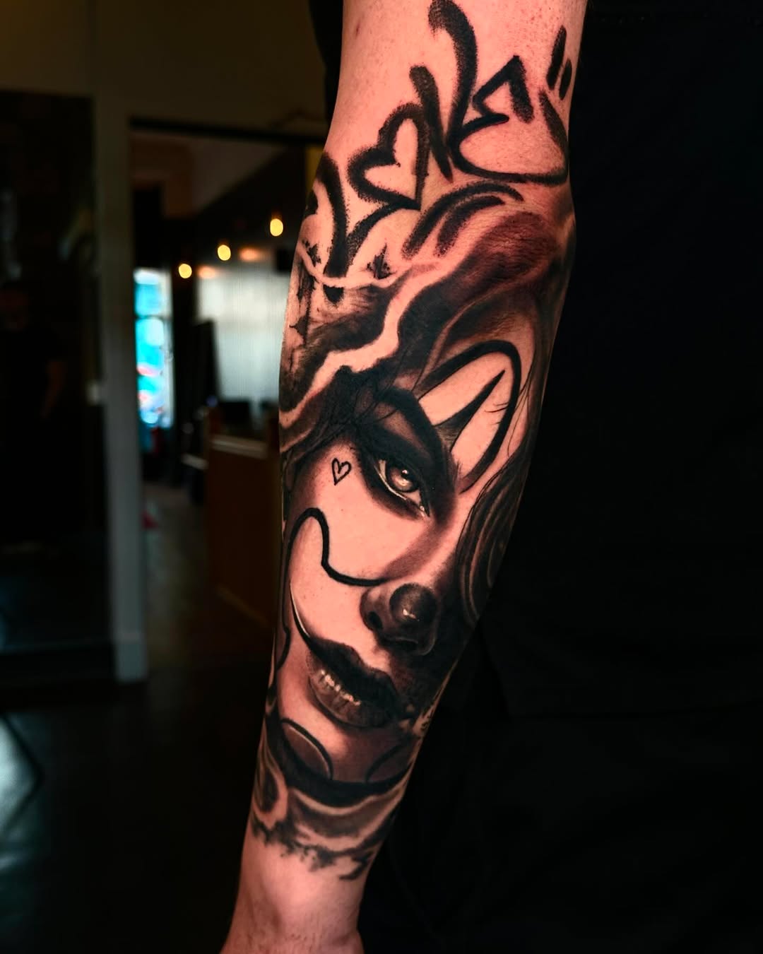 Black and grey portrait tattoo of a horned demon or devil face with detailed shading on the leg.