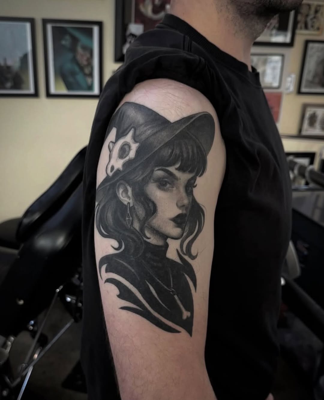 Black and grey portrait tattoo of a woman with wavy hair and decorative headpiece on upper arm.