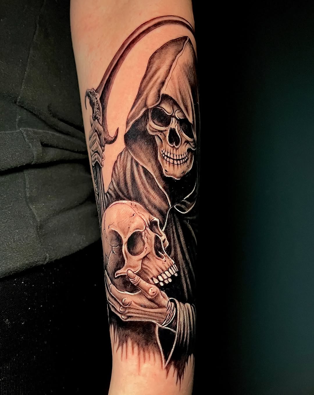 Grim reaper holding skull on forearm with detailed shading and robed figure in black and grey ink.