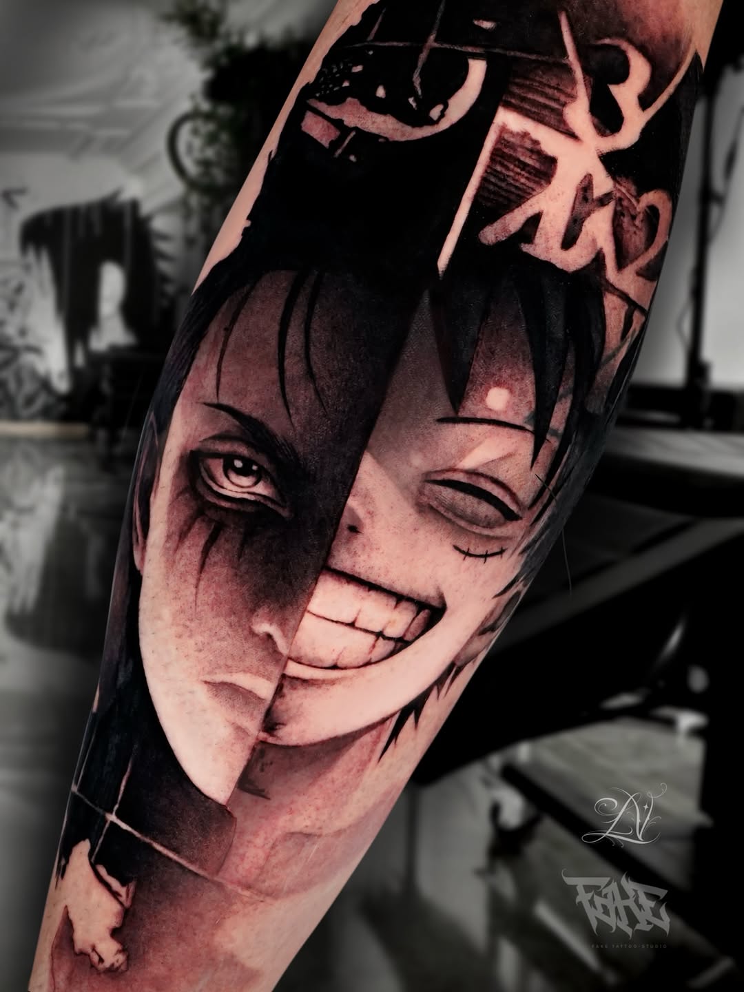 Forearm tattoo of a split anime character face, one side shadowed with sharp eye, other side smiling, with kanji text above.