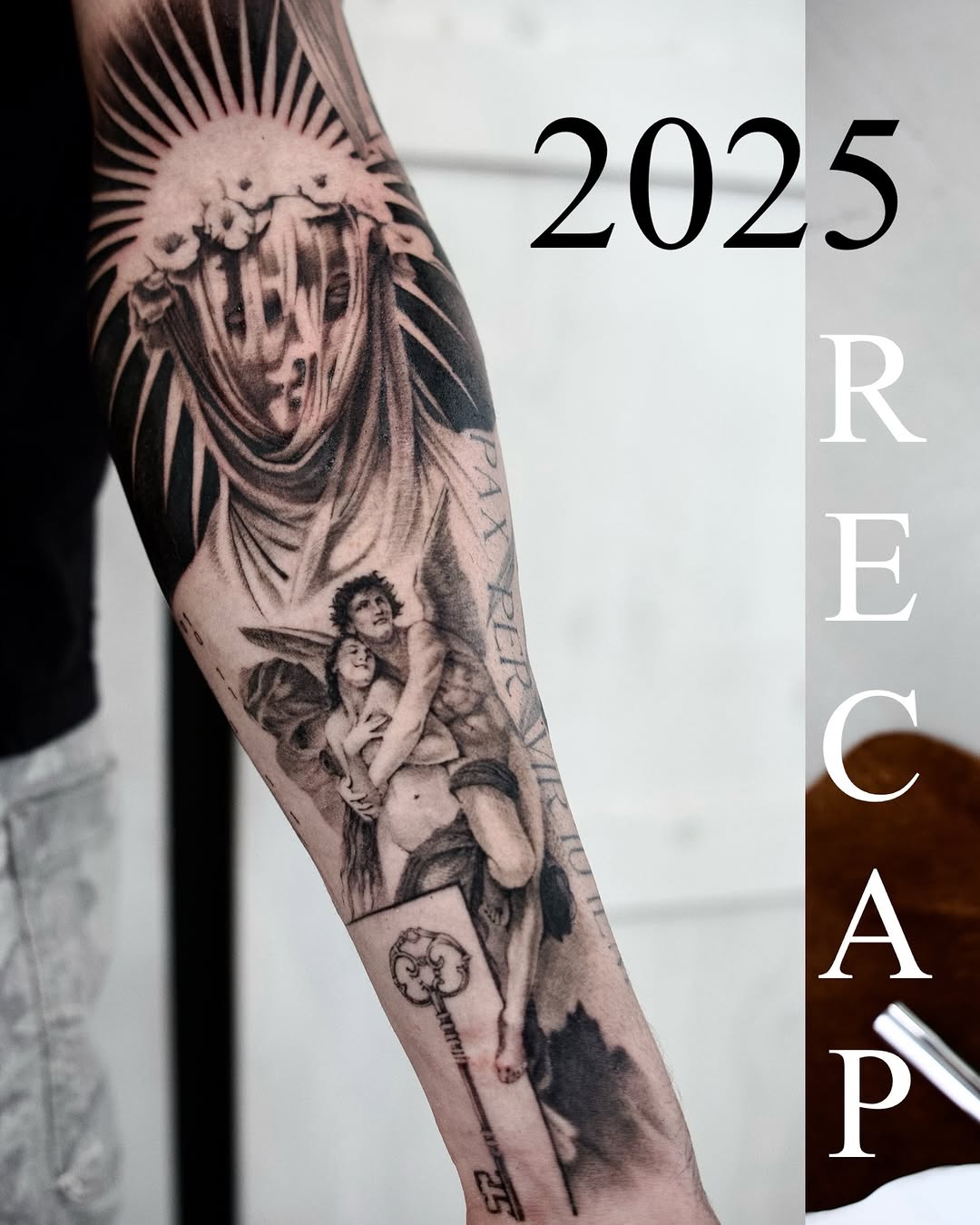 Black and grey arm sleeve featuring religious figures including angels, a winged deity, and cherubs with ornate details and text elements.