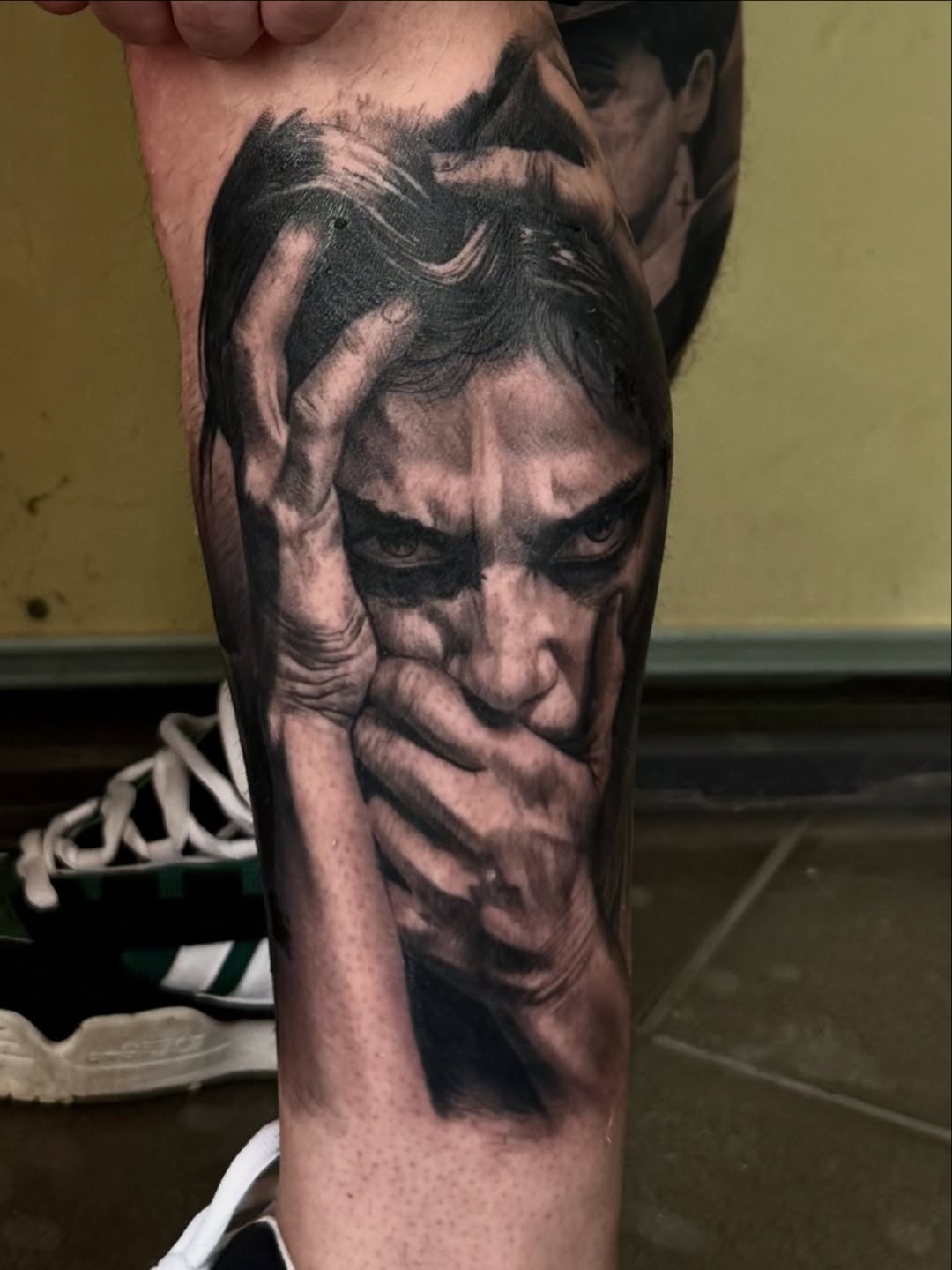 Black and grey realistic portrait tattoo of a man's face on the leg, featuring detailed shading and facial features.