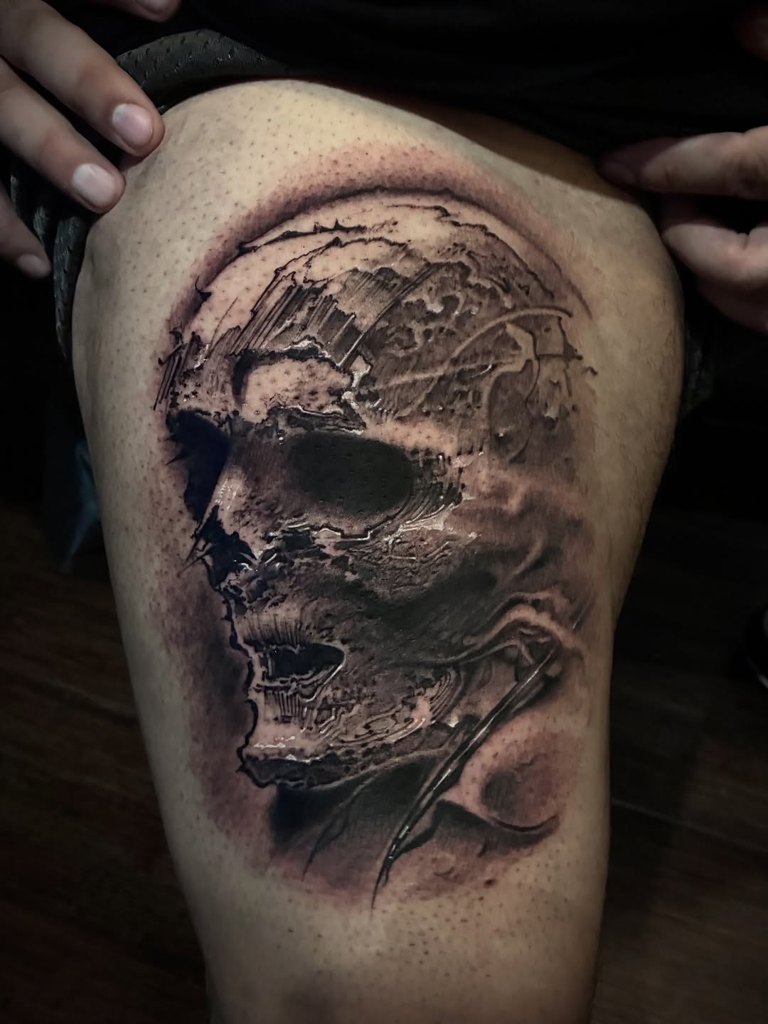 Black and grey skull tattoo with detailed shading on upper thigh, showing anatomical bone structure and depth.
