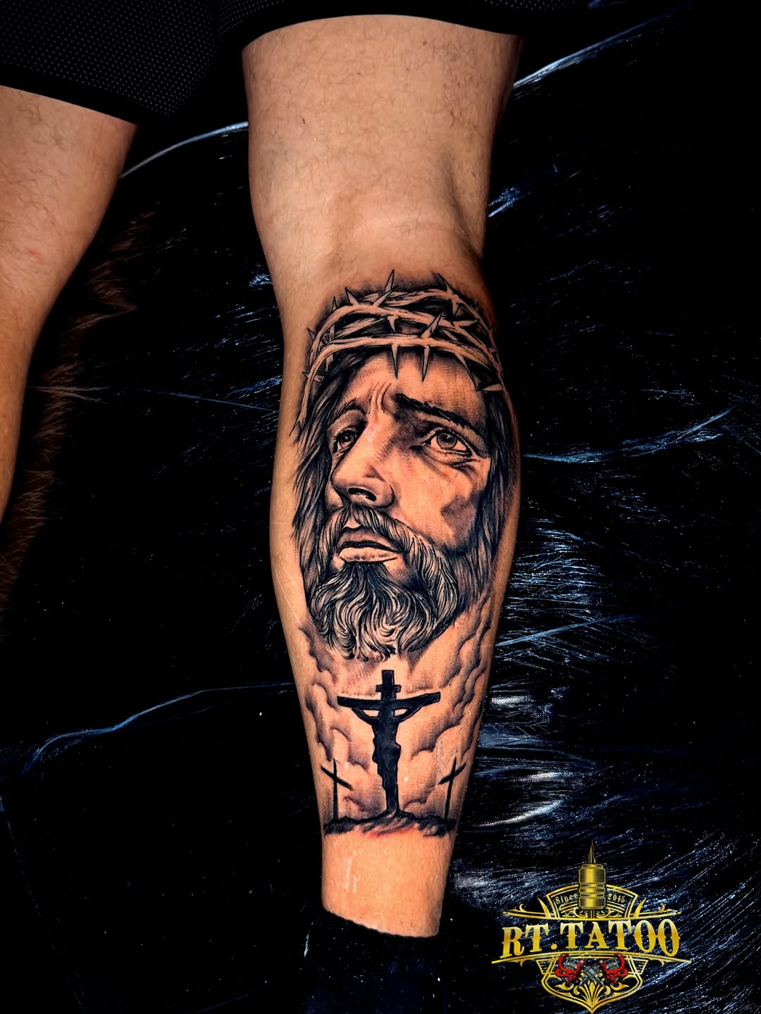 Portrait of bearded man with crown of thorns and crucifix below on calf, black and grey monochrome.