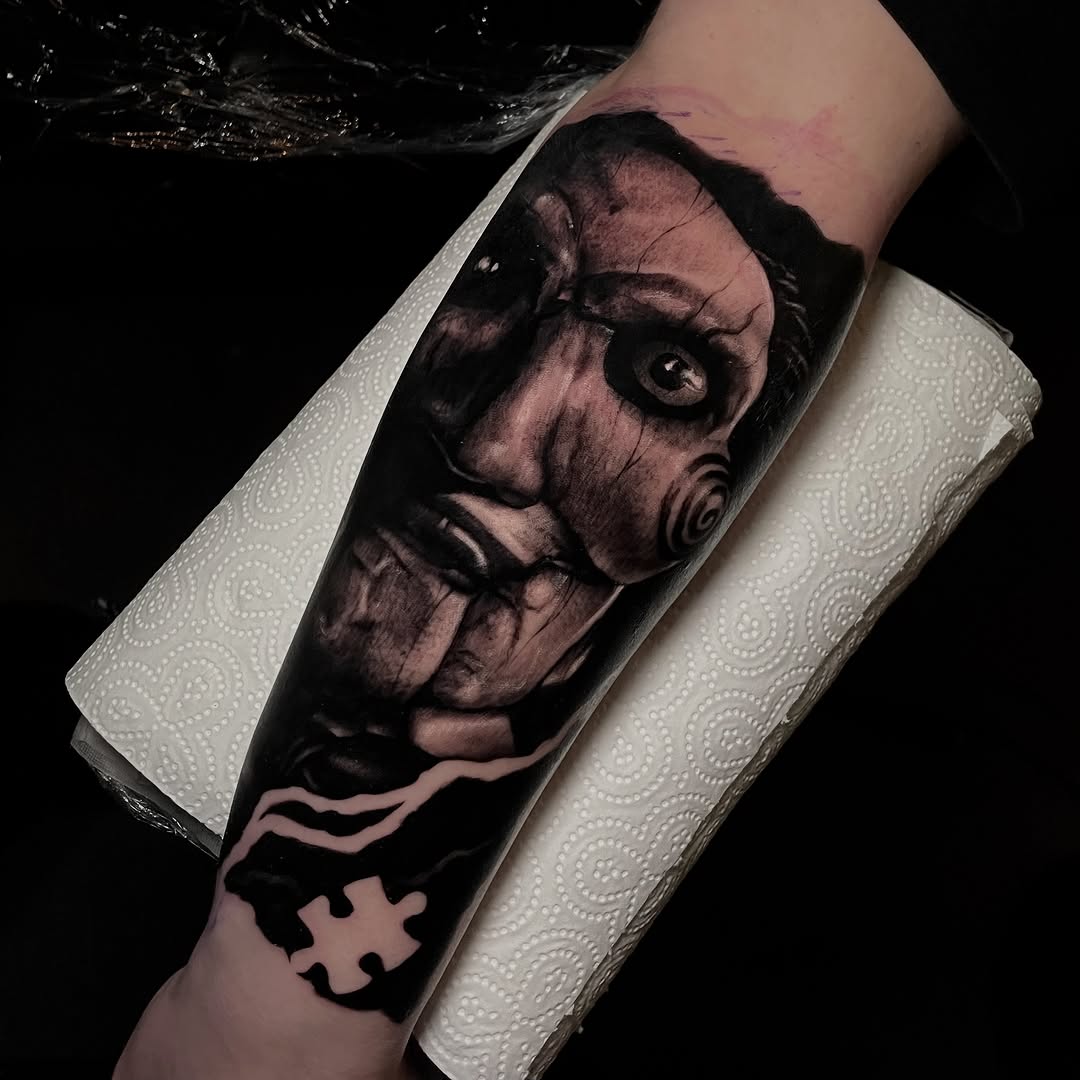 Monochromatic portrait of a face with dramatic expression and spiral detail on forearm, black and grey realism with puzzle piece element below.