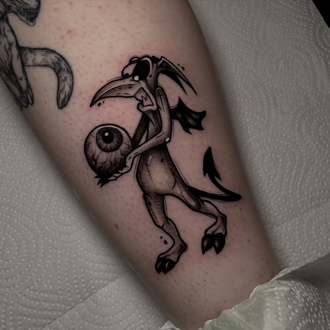 A skeletal creature with a long beak holds a large eyeball, rendered in dark linework on the thigh.