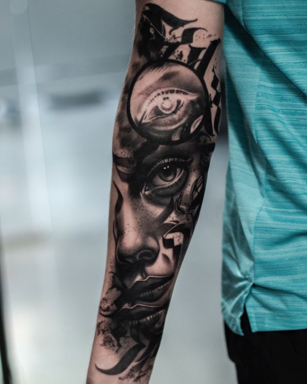Black and grey realistic portrait tattoo on forearm featuring multiple faces with expressive eyes and detailed shading.