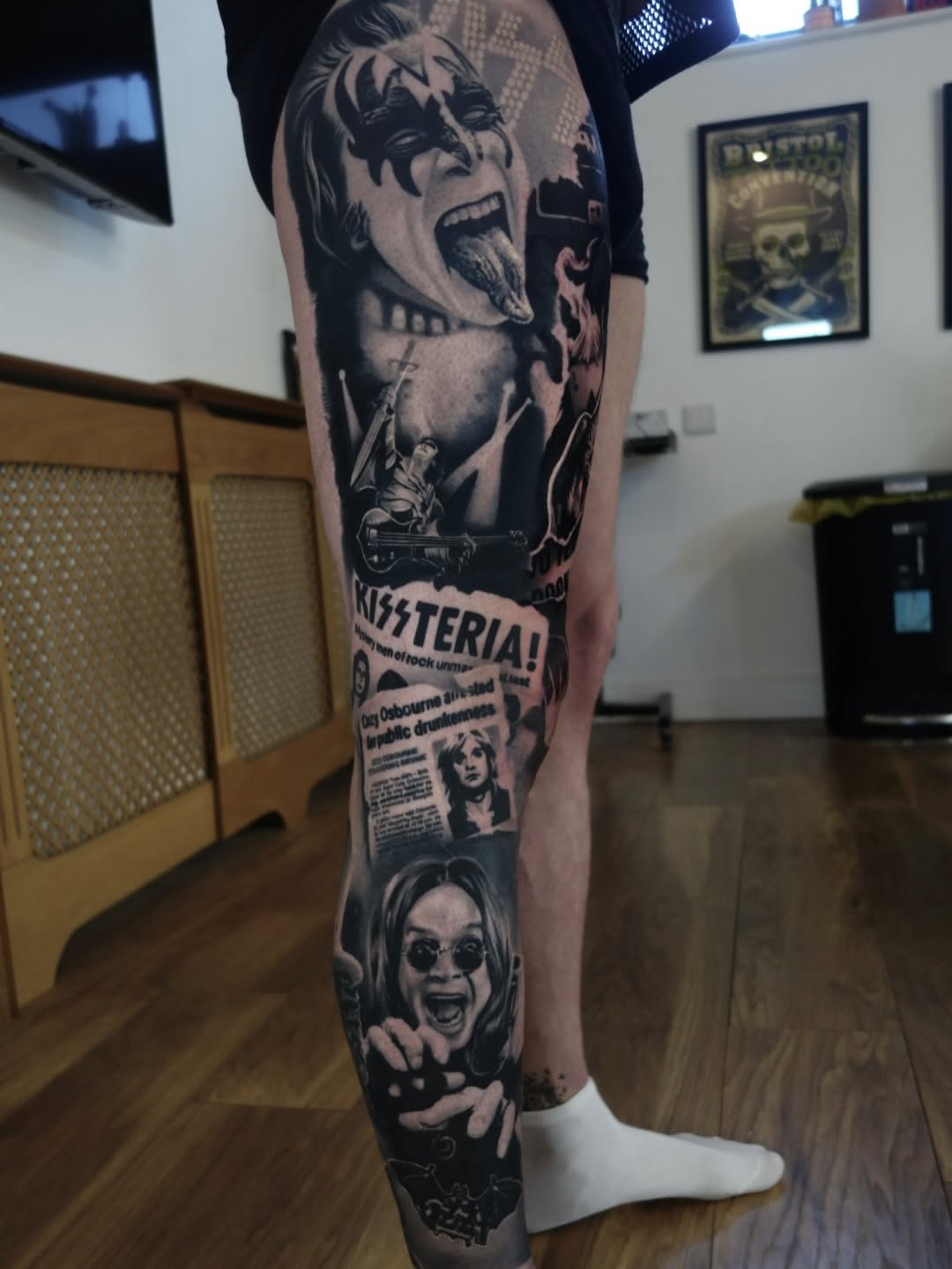Black and grey leg sleeve featuring portrait of musician with dramatic makeup, guitar, and vintage newspaper clipping with text.
