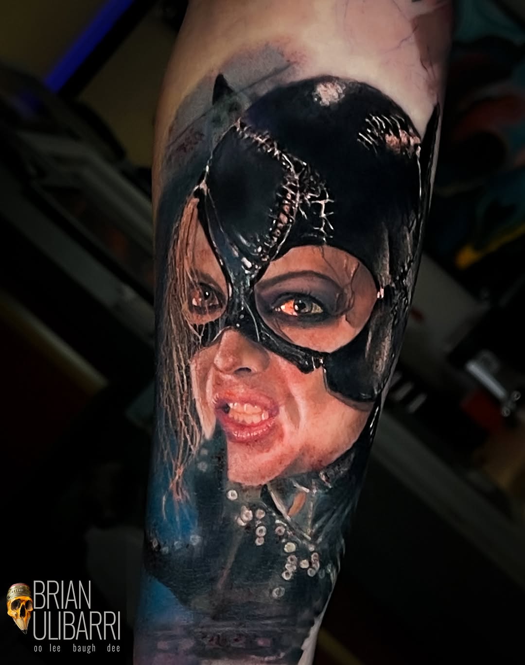 A woman wearing a black mask and studded collar, rendered in color realism on the upper arm with realistic skin tones and detailed facial features.