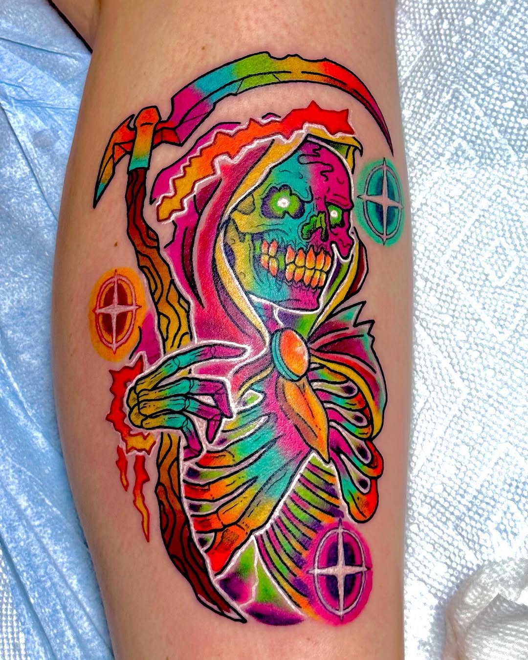 A colorful skeleton head with anatomical ribcage and radiating design elements featuring glowing eye details on the calf.