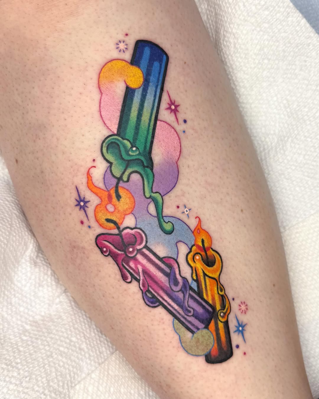 Colorful magical wand tattoo with flames, vines, and stars on the calf, featuring gradient rainbow hues.