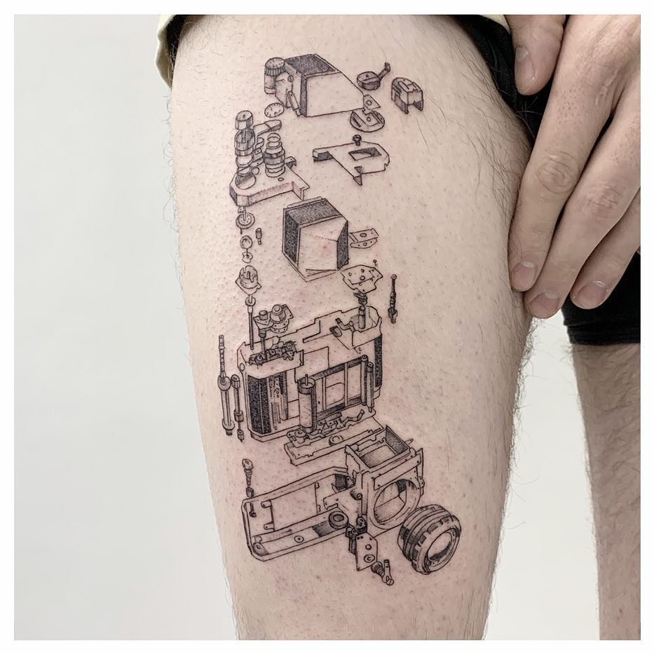 Exploded technical diagram of a vintage camera showing disassembled internal components and lens, rendered in black ink on thigh.