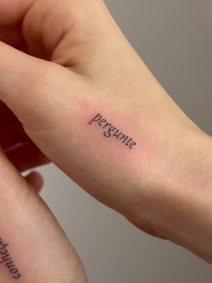Small delicate script tattoo reading 'perfume' on inner arm with hairline-thin linework.