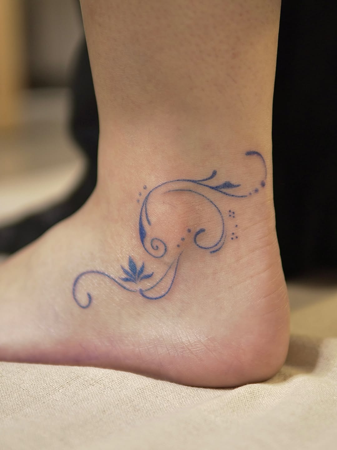 Delicate blue line-work floral and vine design with scrolling flourishes on the ankle.