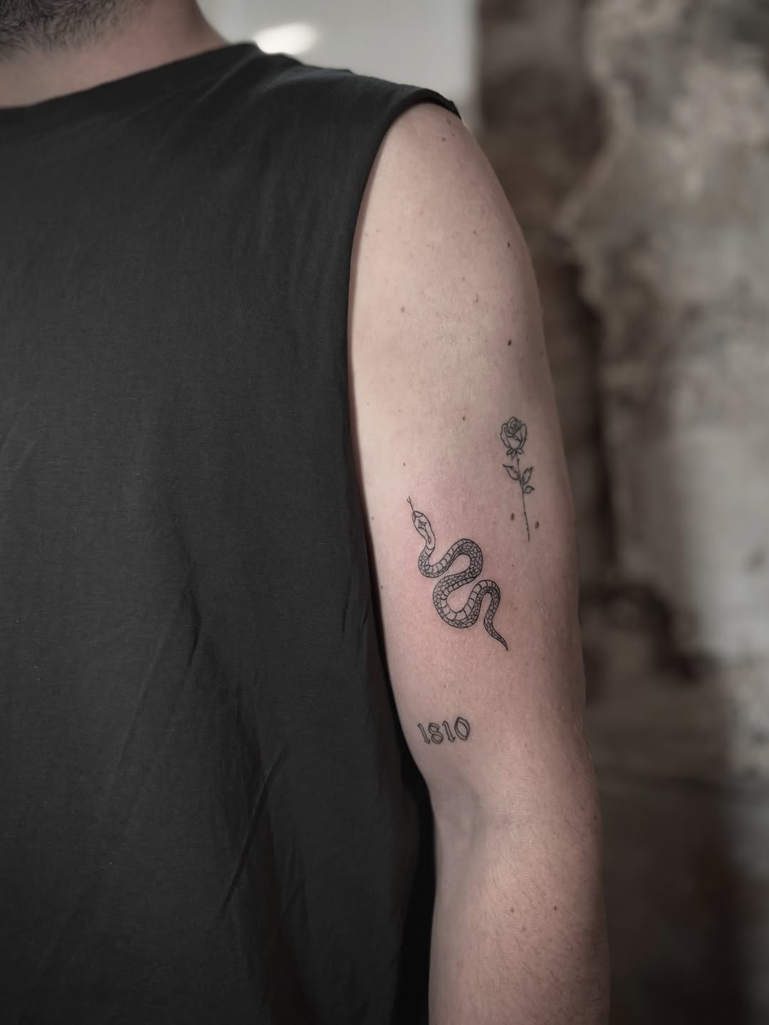 Snake and rose designs with numerals on upper arm, thin linework style.