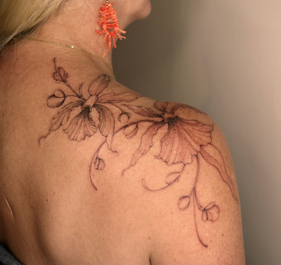 Delicate line-work flowers with fine linework and minimal shading spanning the shoulder and upper back area.