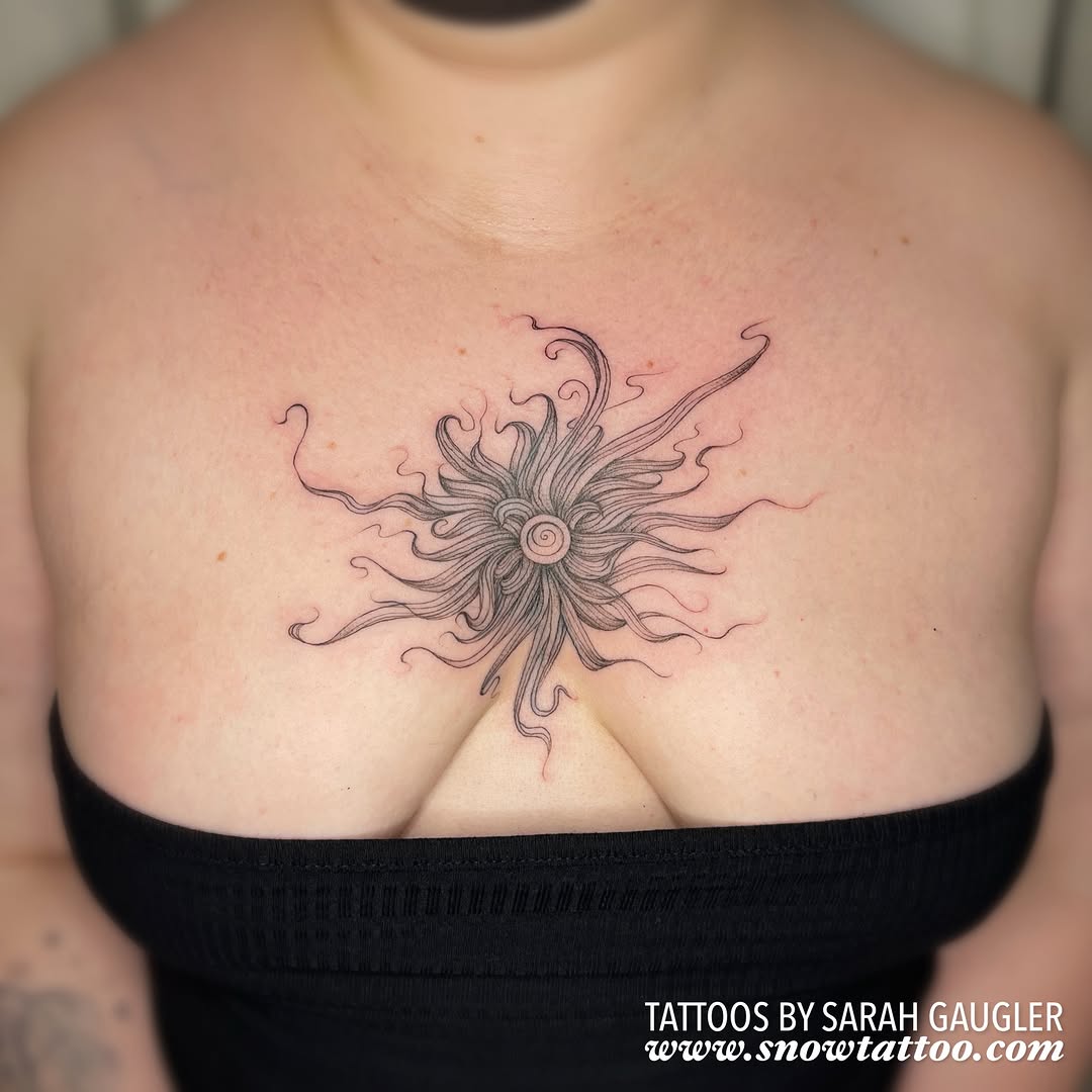 Delicate line-work sun with flowing tentacle-like rays radiating outward, centered on chest.