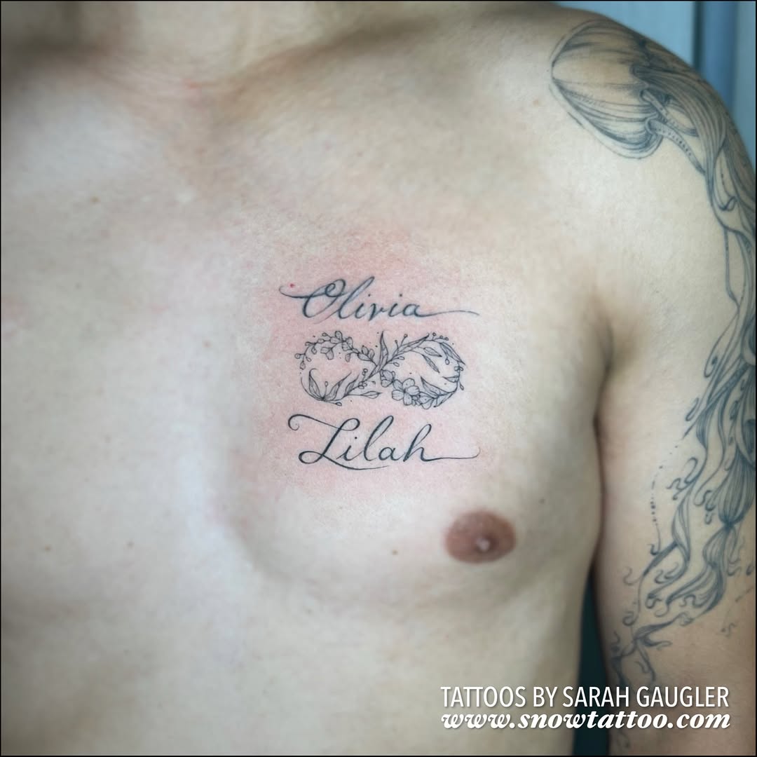 Two names in cursive script with decorative floral wreath between them on chest.