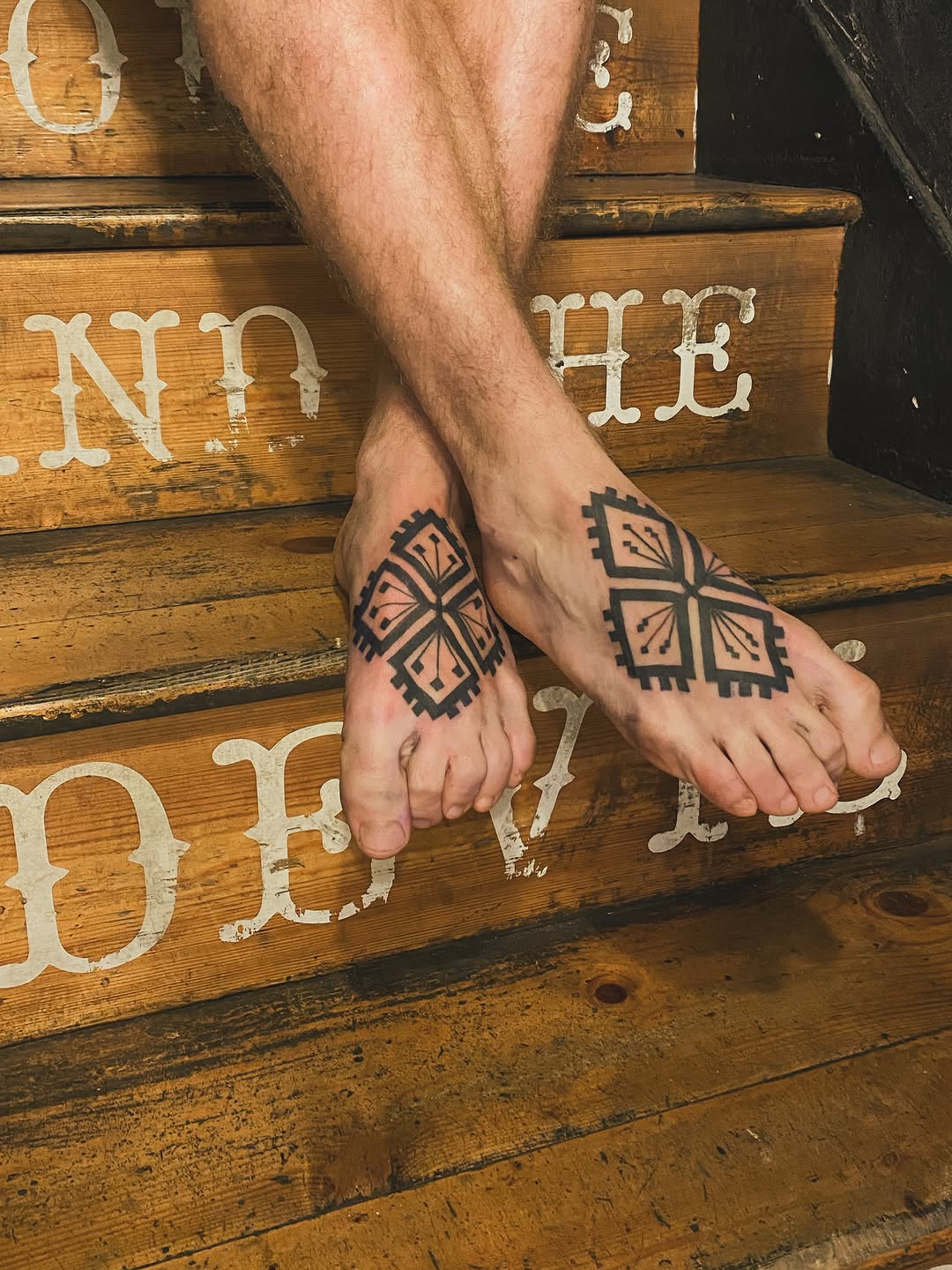 Matching geometric diamond and cross patterns with symmetrical linework on both feet.