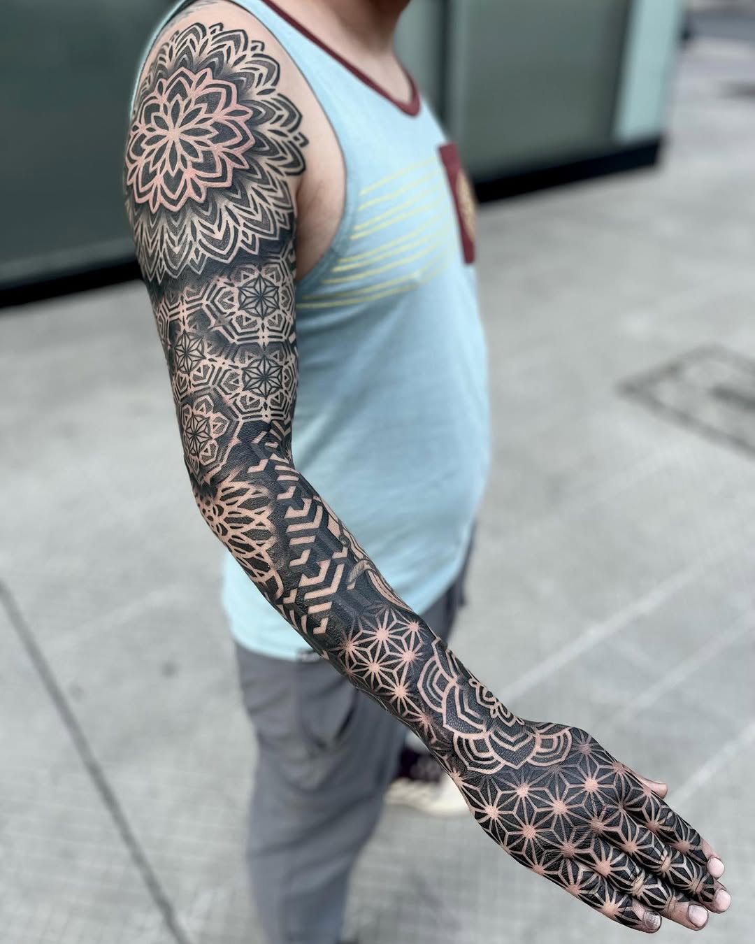 Full mandala and geometric pattern sleeve tattoo covering shoulder to wrist in black ink with intricate symmetrical designs.