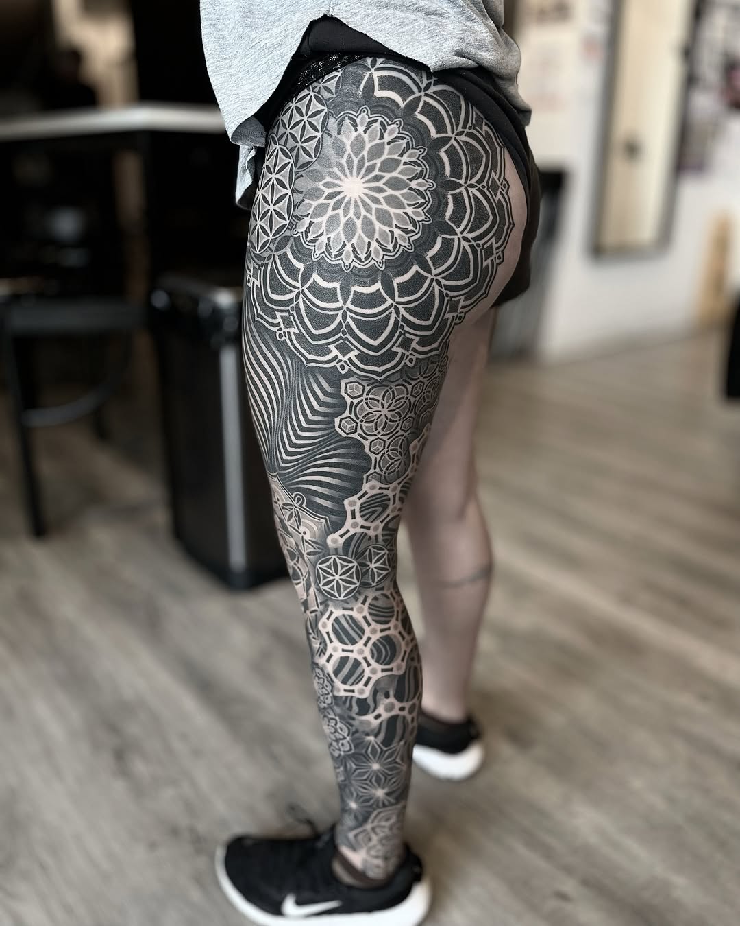 Full leg sleeve featuring intricate geometric mandalas, flower of life patterns, and symmetrical dotwork ornamental designs in black and grey.