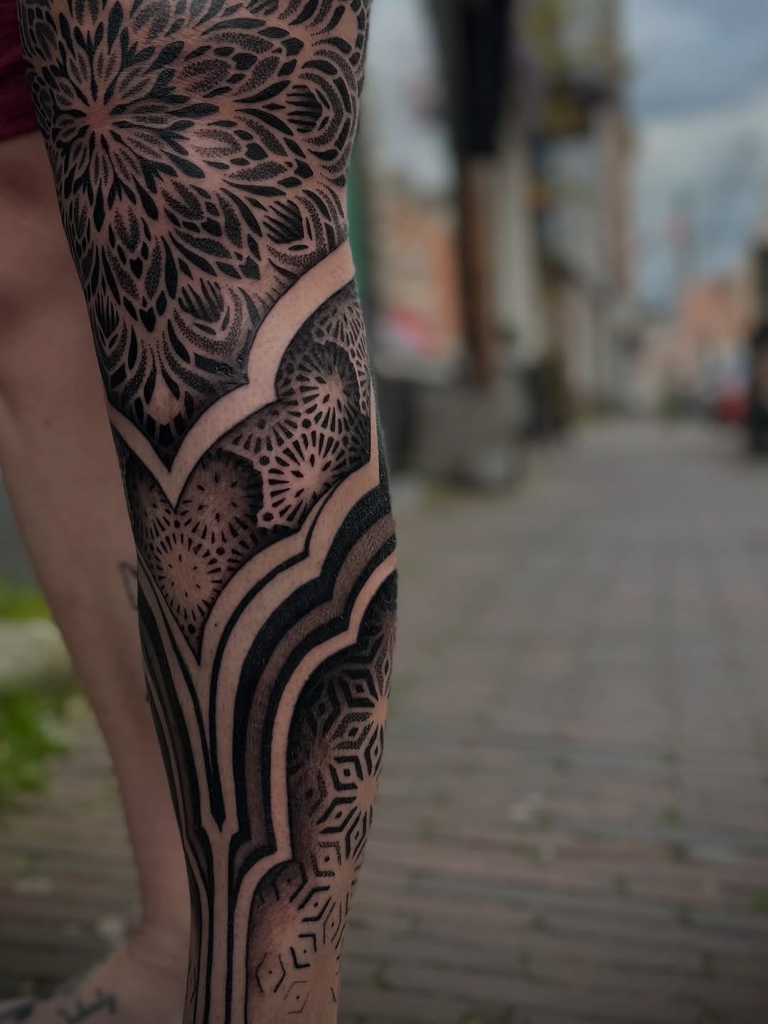 Intricate geometric and mandala dotwork tattoo covering the leg with ornamental circular patterns and flowing linework.