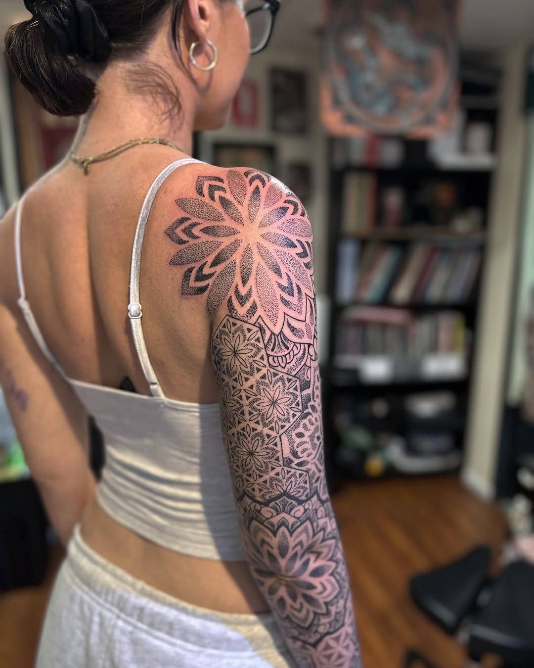 Large mandala-style geometric sleeve tattoo with intricate dotwork stippling and symmetrical petal patterns on the shoulder and upper arm.