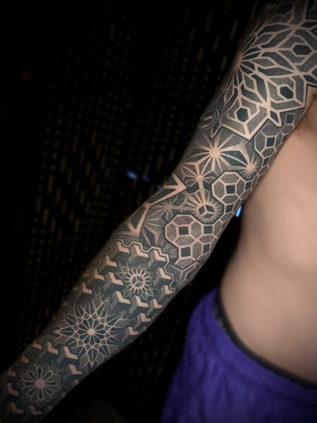 Full-sleeve geometric mandala and sacred geometry pattern with dotwork stippling and symmetrical ornamental designs covering the forearm.