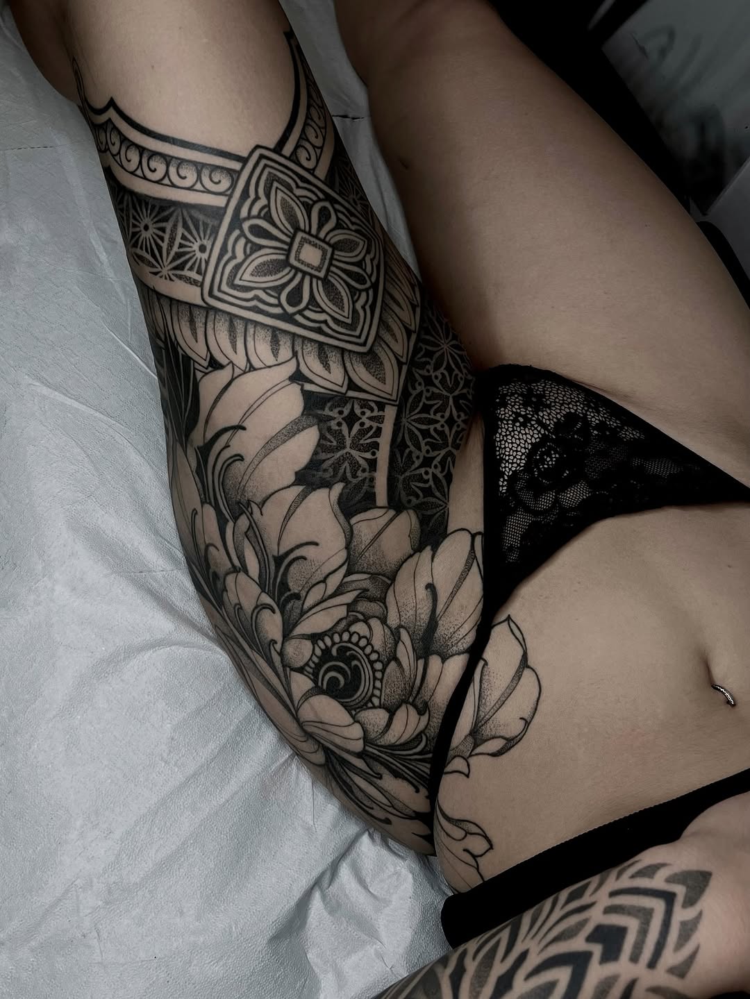 Ornamental sleeve tattoo with geometric mandala patterns, floral motifs, and symmetrical decorative bands on the upper arm.