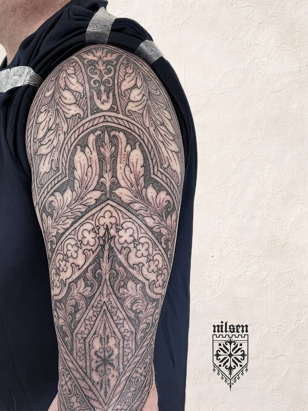 Large-scale ornamental sleeve tattoo featuring symmetrical geometric and floral mandala patterns with intricate linework on upper arm.