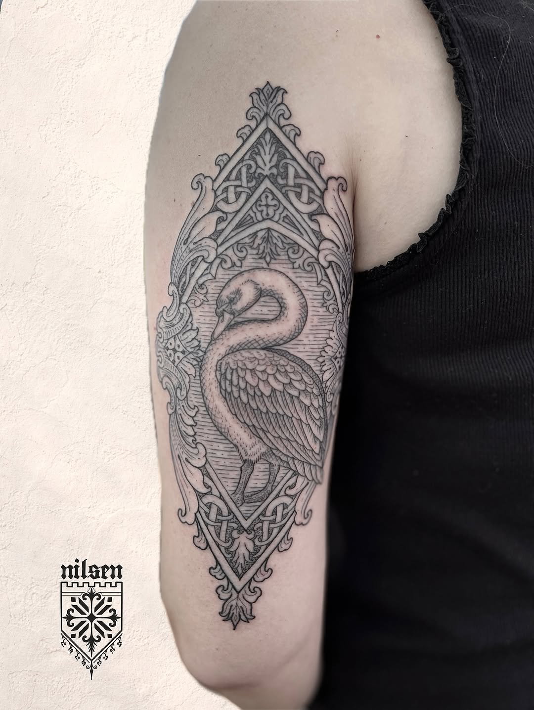 Ornate geometric crane within an elaborate symmetrical architectural frame with Celtic knotwork and decorative flourishes on the upper arm.
